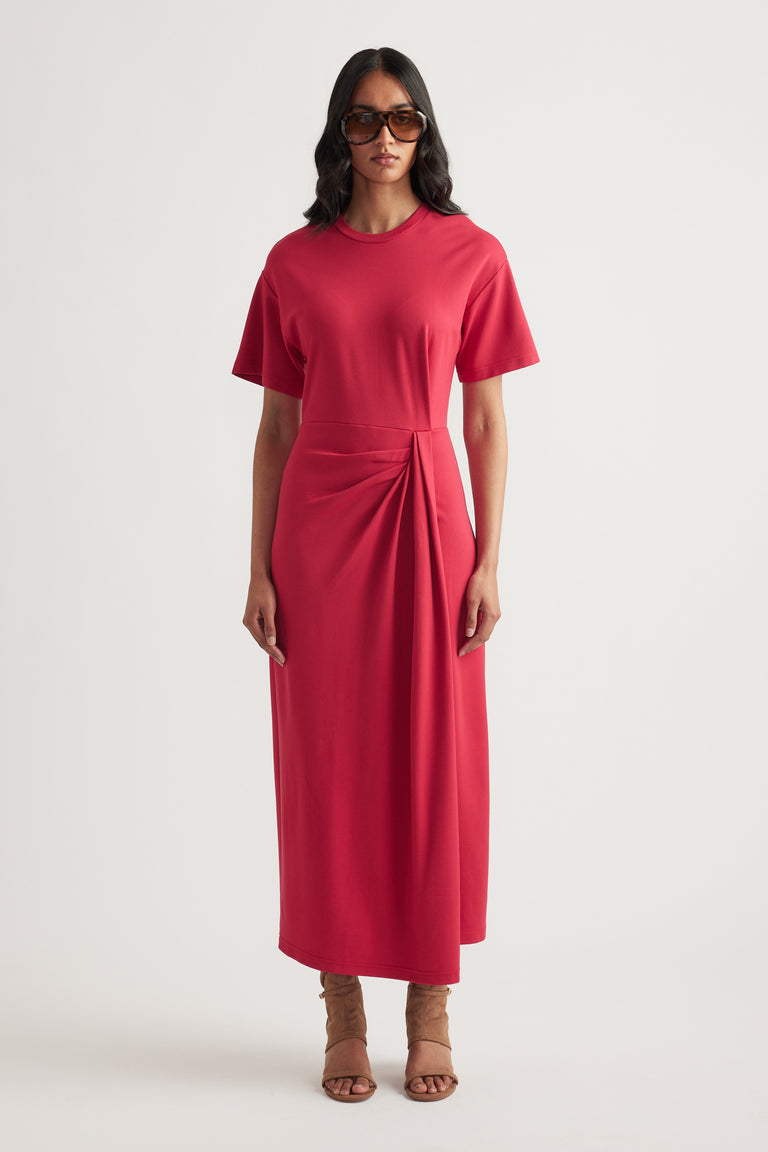 Woman wearing a red short sleeve midi dress with round neck and waist knot detail, styled with sunglasses and sandals