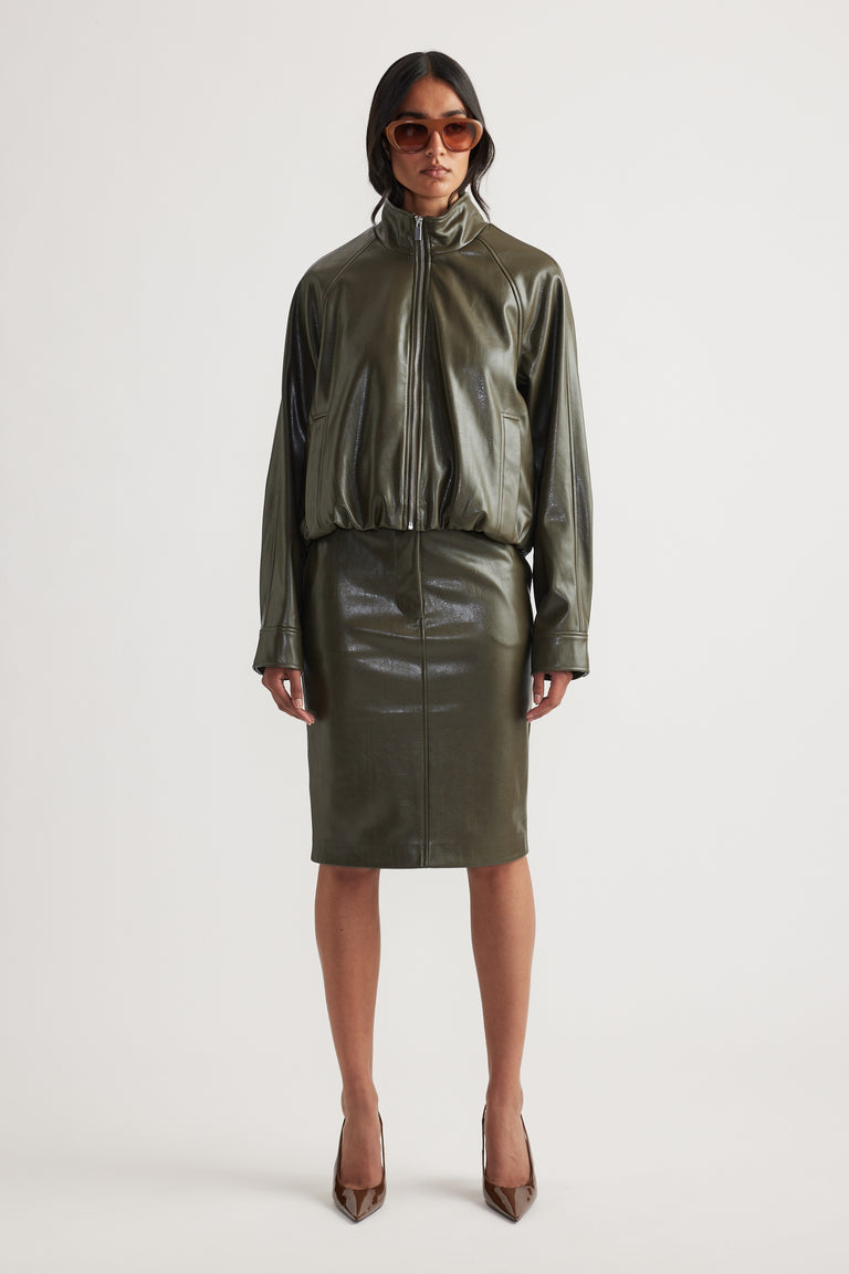 Woman wearing olive green faux leather bomber jacket with matching pencil skirt and brown pointed heels