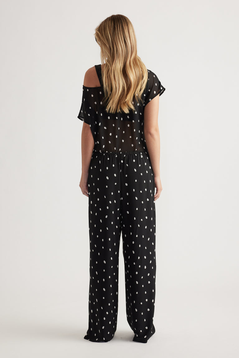 Woman wearing relaxed black sheer georgette pants with white spots and a matching sheer top, back view