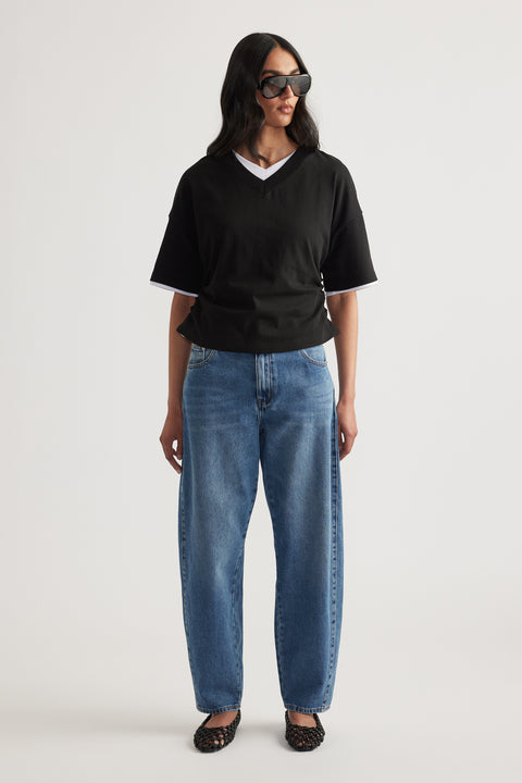 Woman in a black relaxed V-neck short sleeve tee, blue jeans and sunglasses