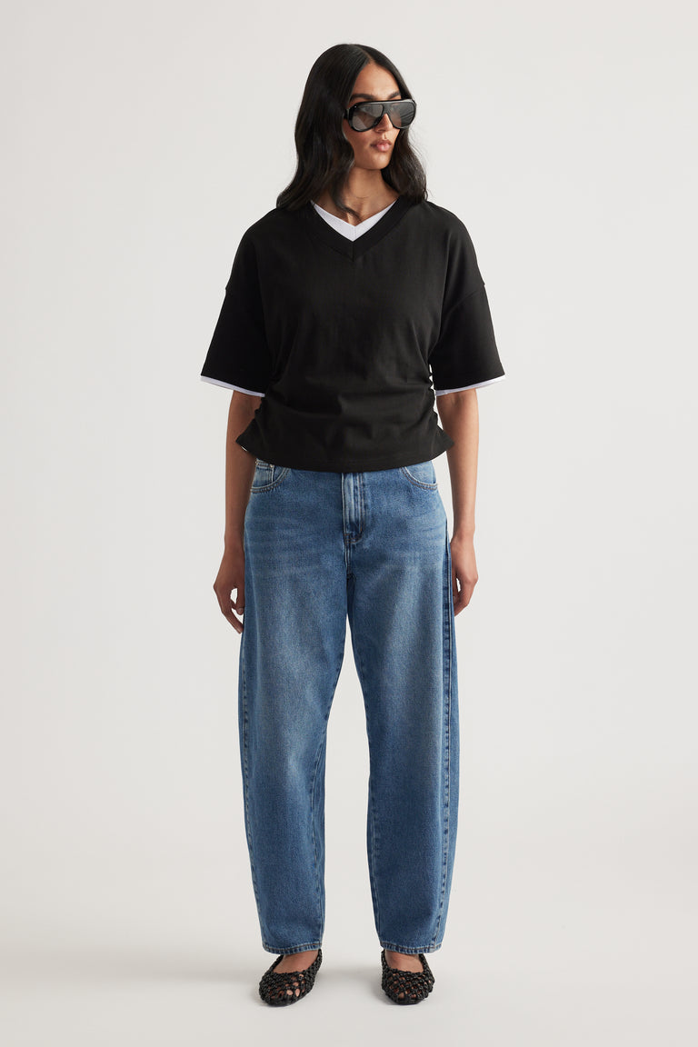 Woman in a black relaxed V-neck short sleeve tee, blue jeans and sunglasses