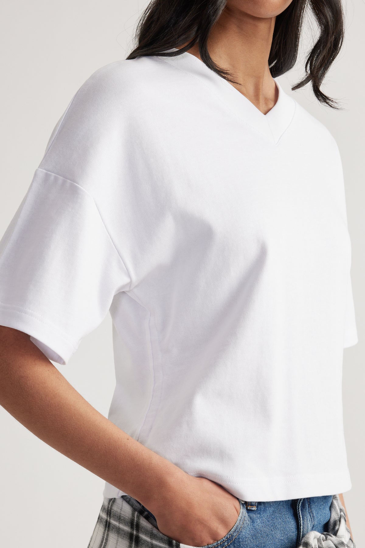 Woman wearing a relaxed white V-neck short sleeve tee with blue jeans