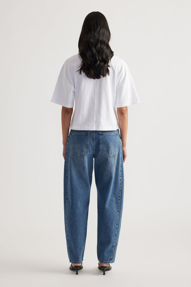 Woman seen from behind wearing a relaxed white short sleeve tee with blue jeans