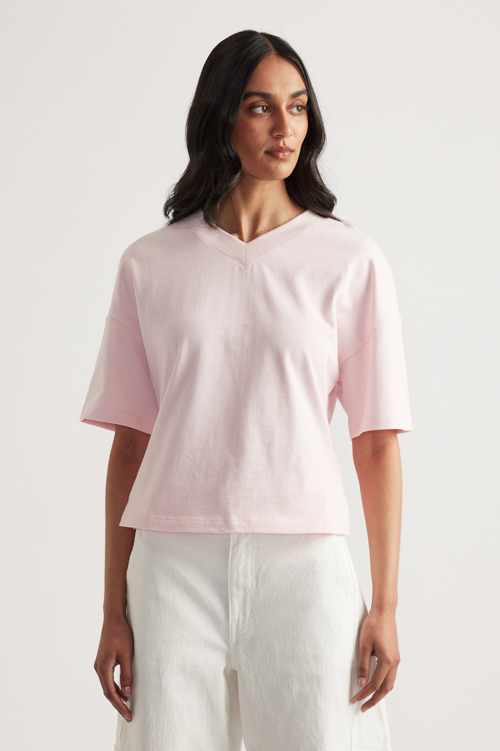 Woman wearing a pale pink relaxed fit V neck tee with white pants