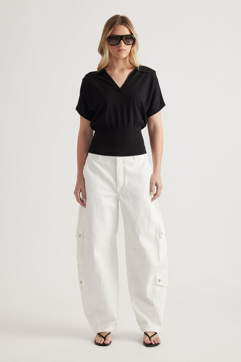 Woman wearing a black short sleeve V neck knit top with white cargo pants and sandals