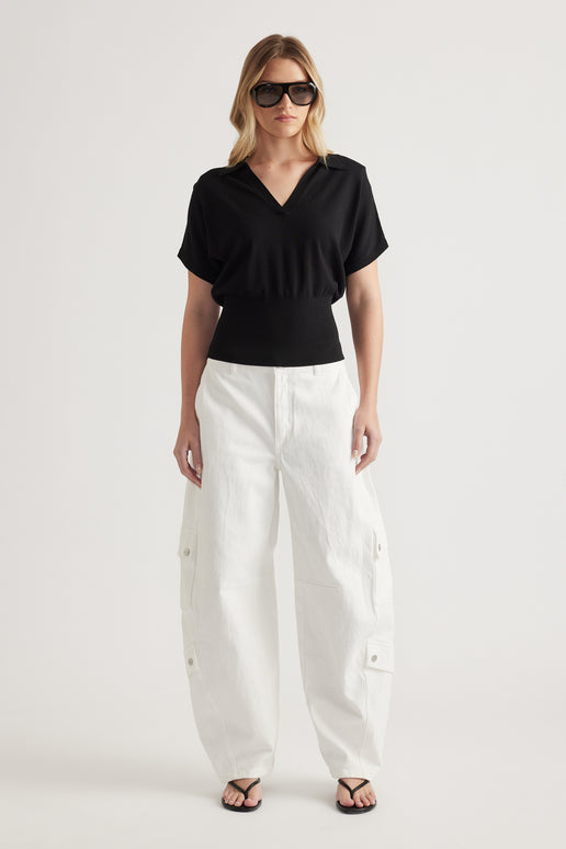 Woman wearing a black short sleeve V neck knit top with white cargo pants and sandals