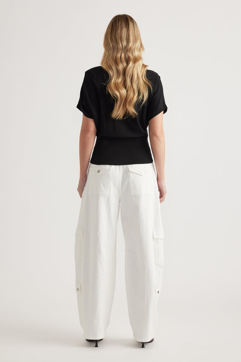 Woman wearing a black short sleeve polo knit top with white cargo pants