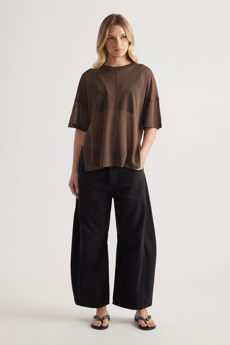 Woman wearing a relaxed brown sheer knit tee with black wide leg pants and strappy sandals