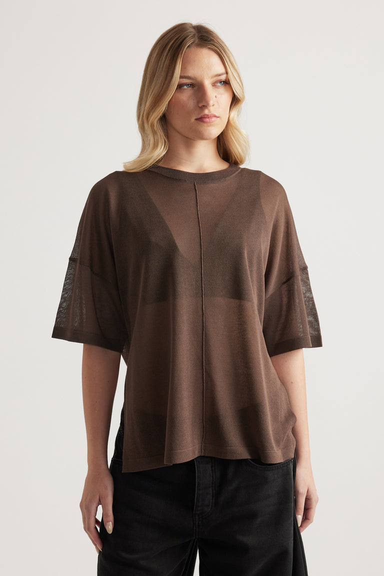 Woman wearing a relaxed brown sheer knit tee with short sleeves and centre seam, styled with black pants