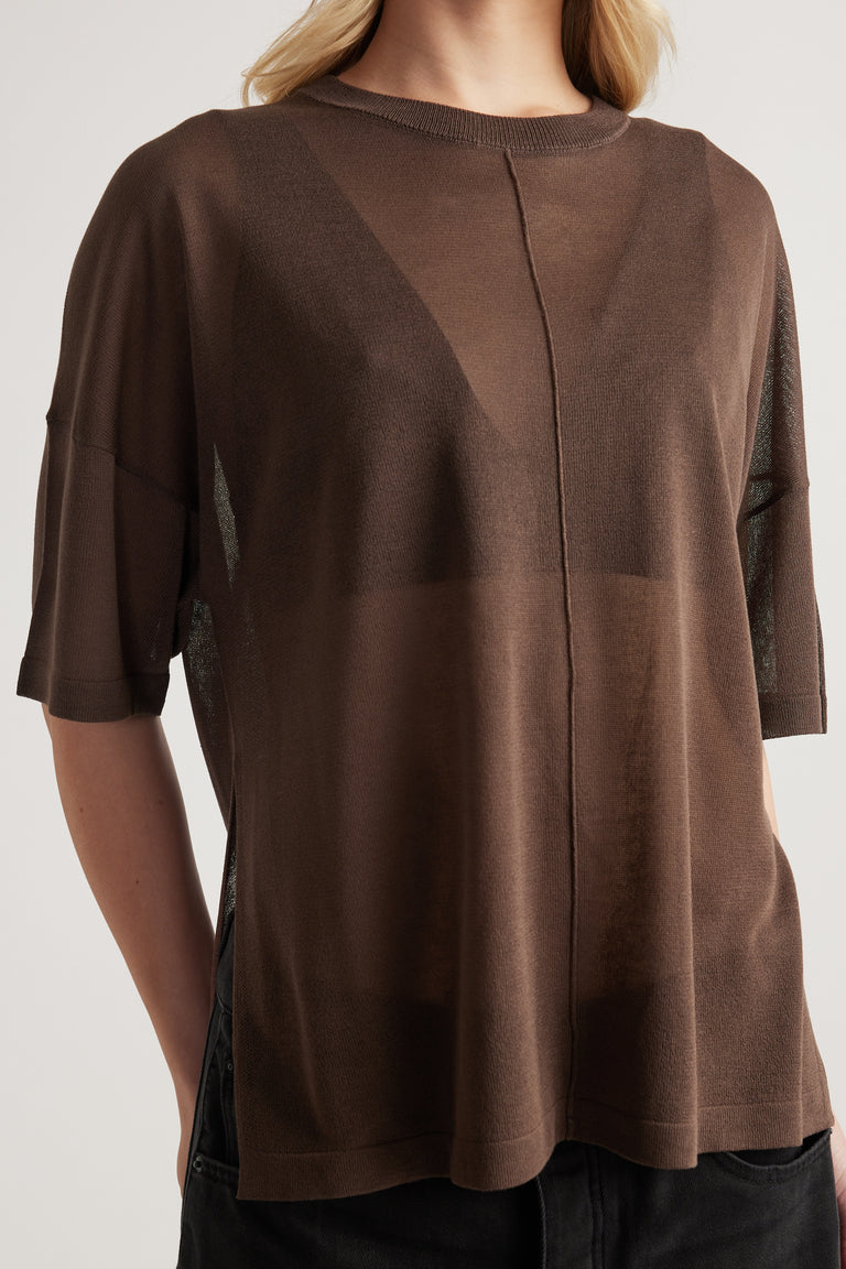 Woman wearing a relaxed brown sheer knit tee with crew neck, short sleeves, centre seam and longline fit