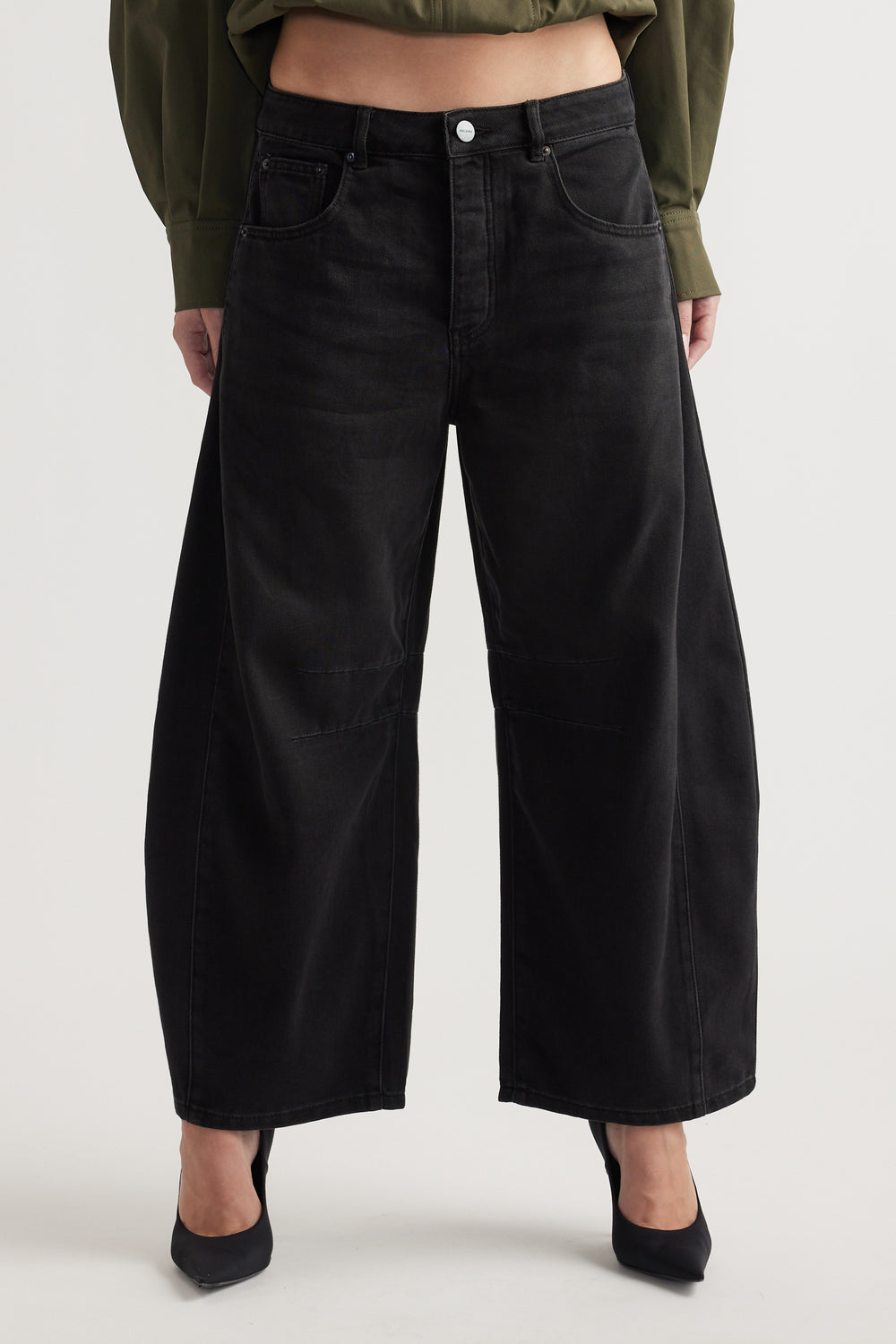High-rise wide-leg black denim jeans with subtle panel detailing, styled with black pointed heels and a cropped top.