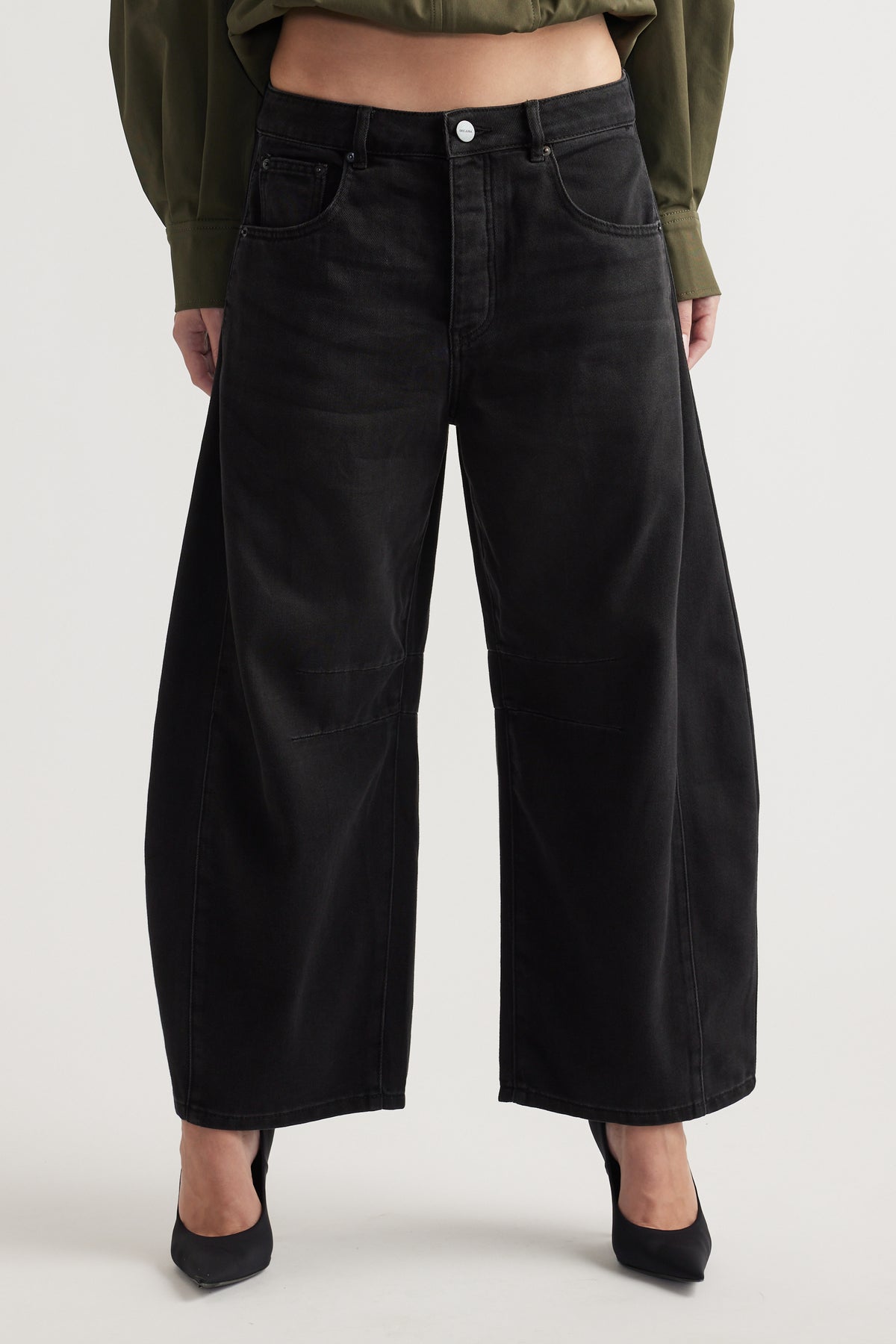 High-rise wide-leg black denim jeans with subtle panel detailing, styled with black pointed heels and a cropped top.