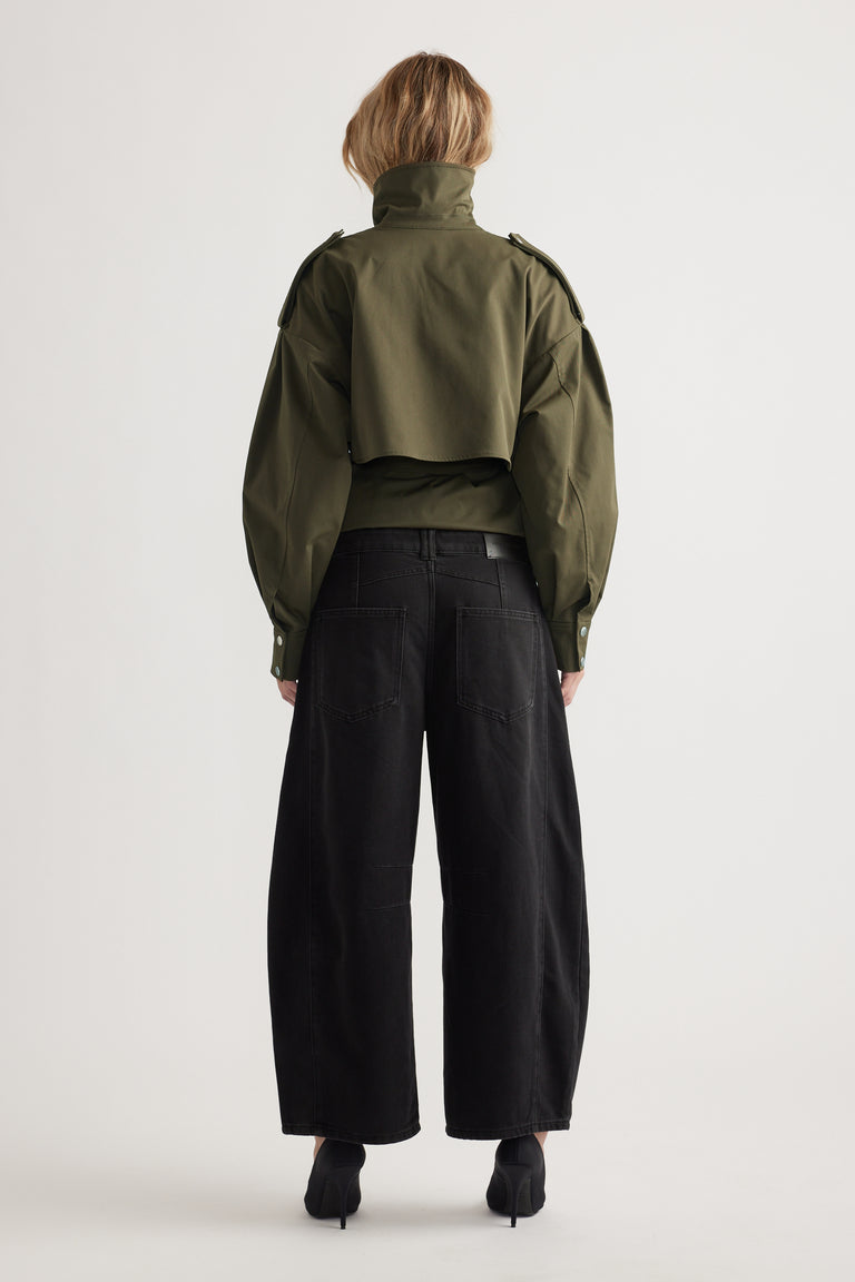 Back view of woman wearing loose black wide-leg jeans paired with structured olive green cropped jacket
