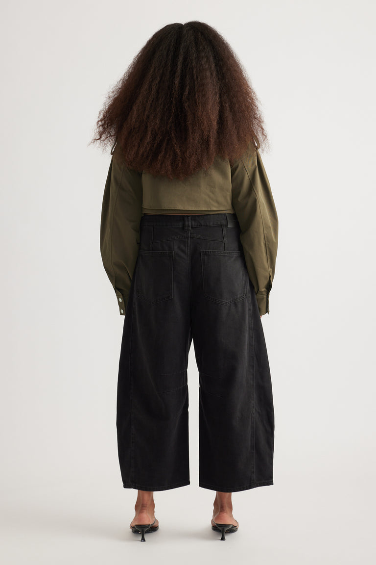 Back view of woman in black cropped barrel jeans, olive jacket and kitten heels