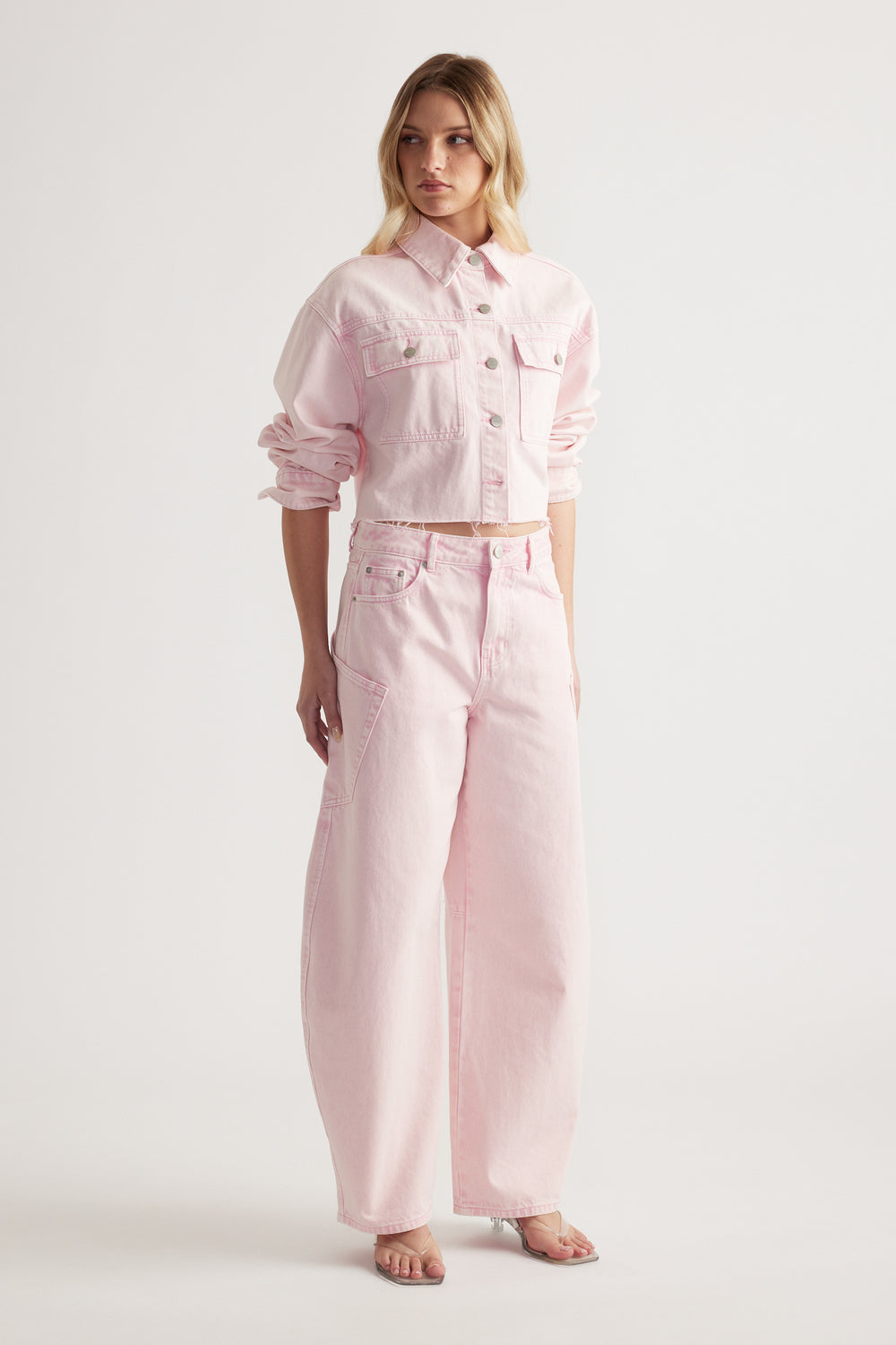 Woman wearing a cropped pink denim jacket with matching barrel leg cargo jeans and sandals