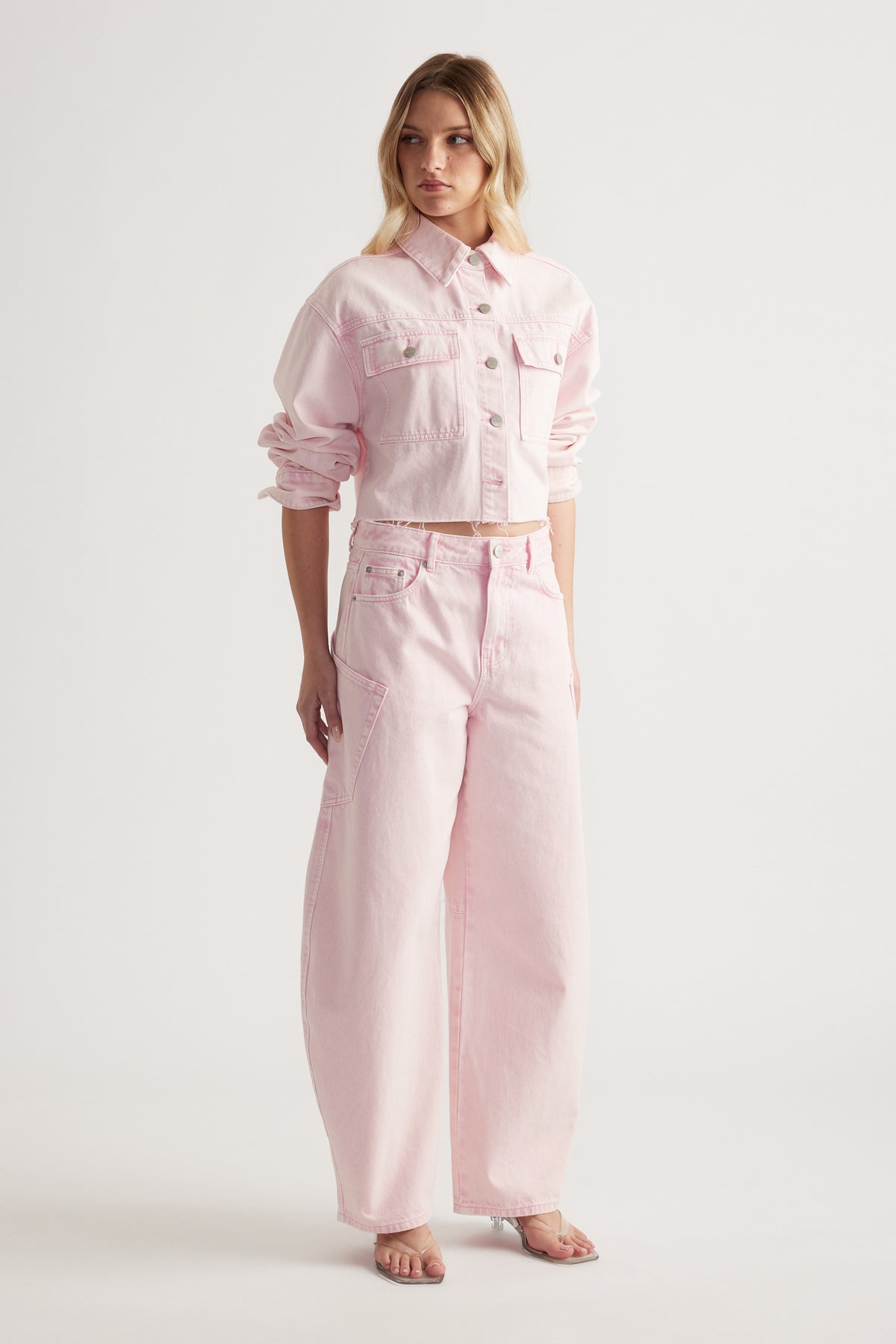 Woman wearing a cropped pink denim jacket with matching barrel leg cargo jeans and sandals