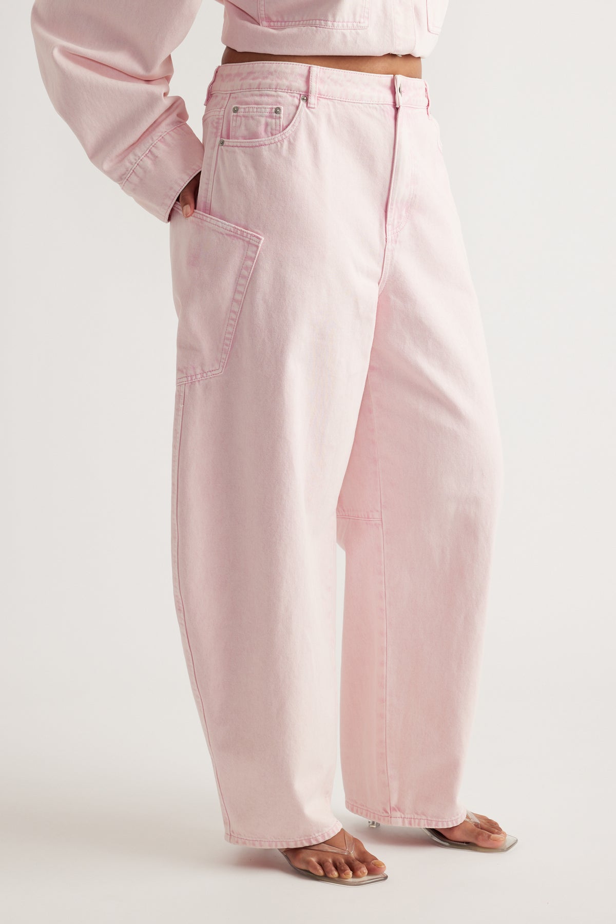 Model wearing pink barrel-leg cargo jeans with oversized pockets, a cropped top and flat sandals