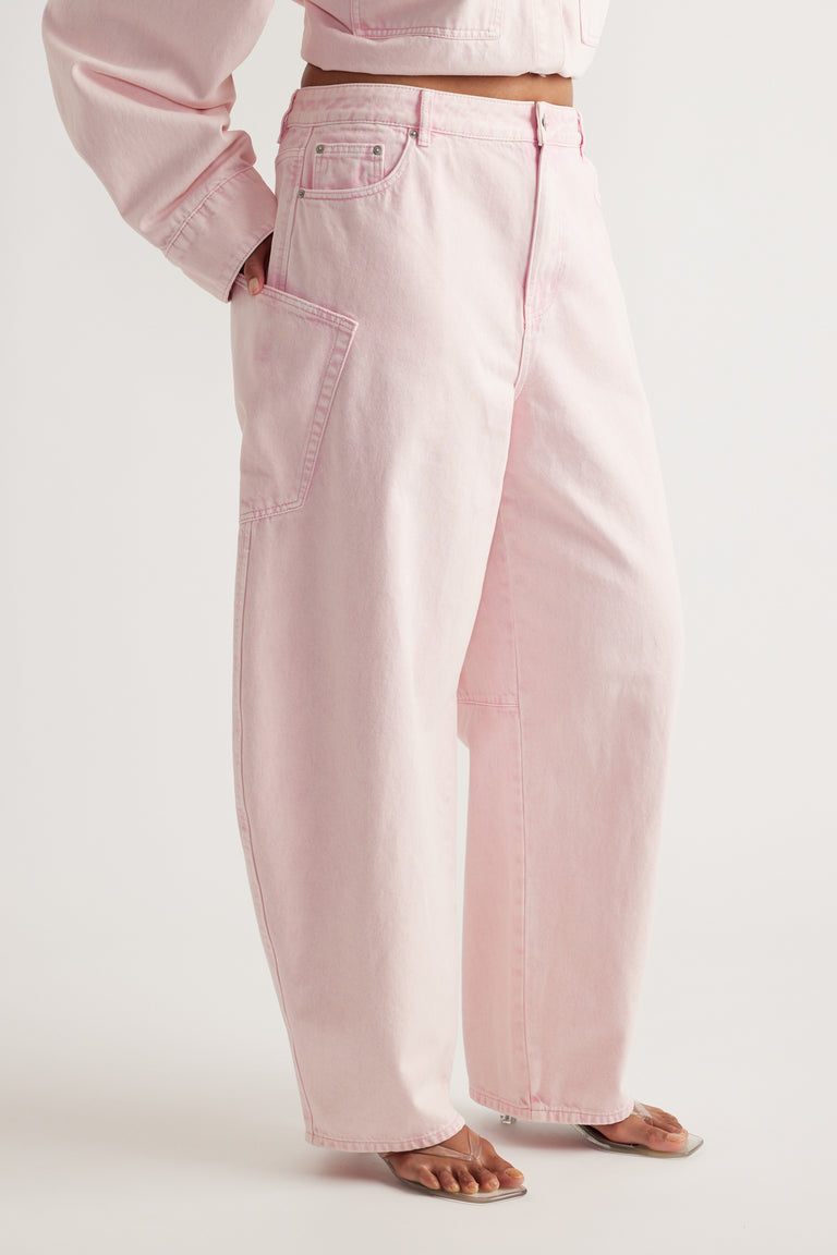 Model wearing pink barrel-leg cargo jeans with oversized pockets, a cropped top and flat sandals