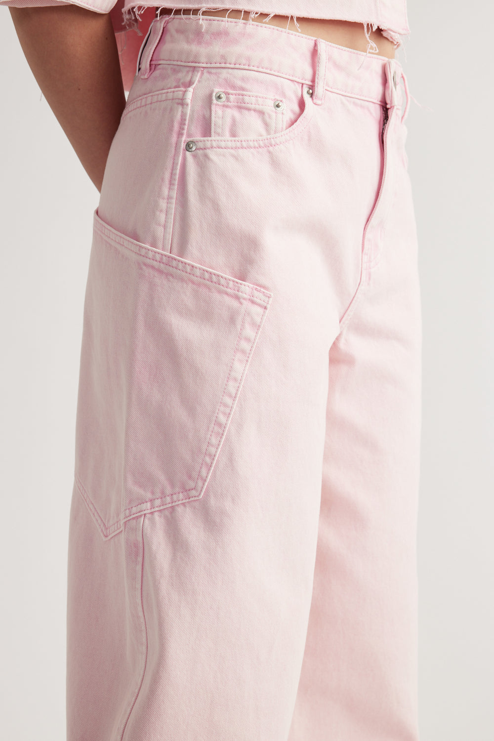 Model wearing pink cargo barrel jeans with oversized utility pockets and tapered legs
