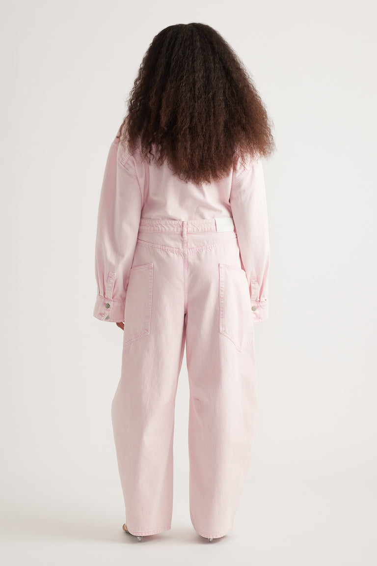 Back view of a model wearing pink barrel-leg cargo jeans with oversized pockets and a matching long-sleeve top