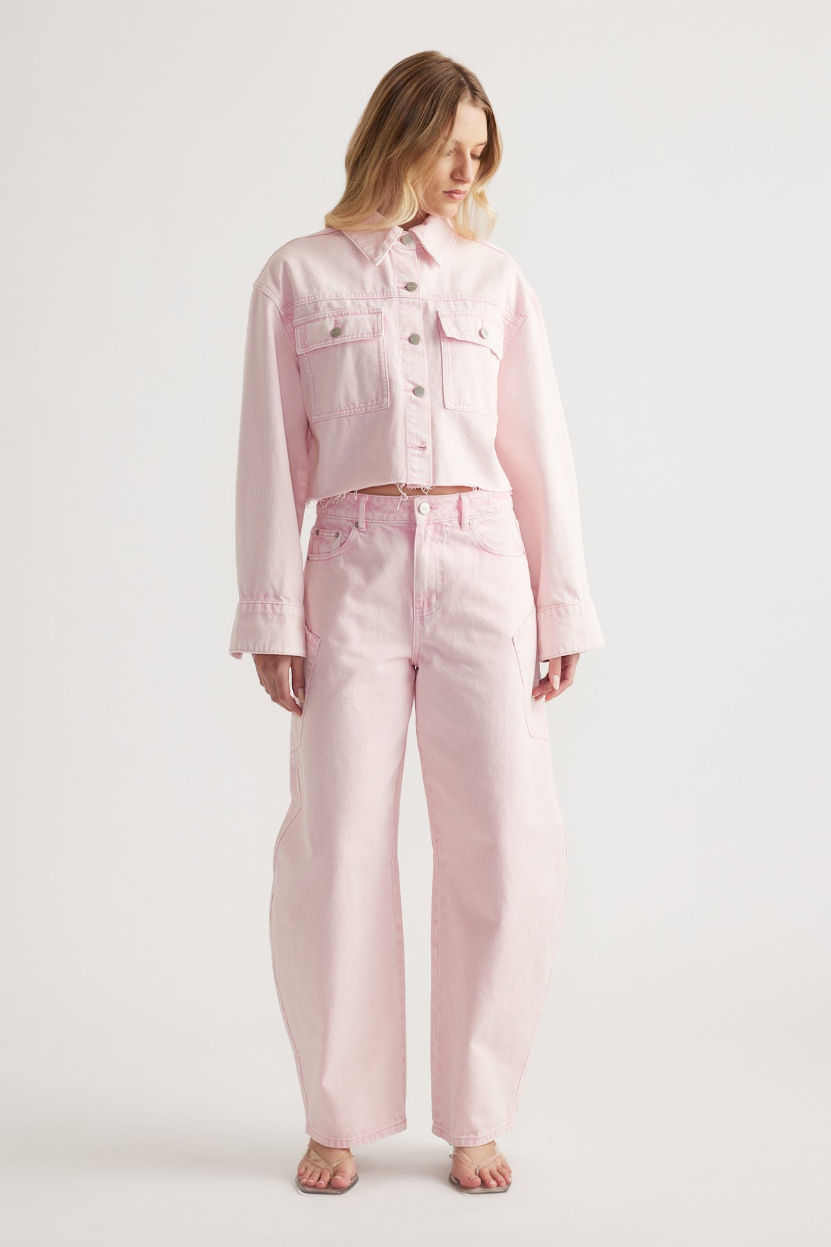 Woman wearing a cropped pink denim shirt with patch pockets and matching high waisted jeans