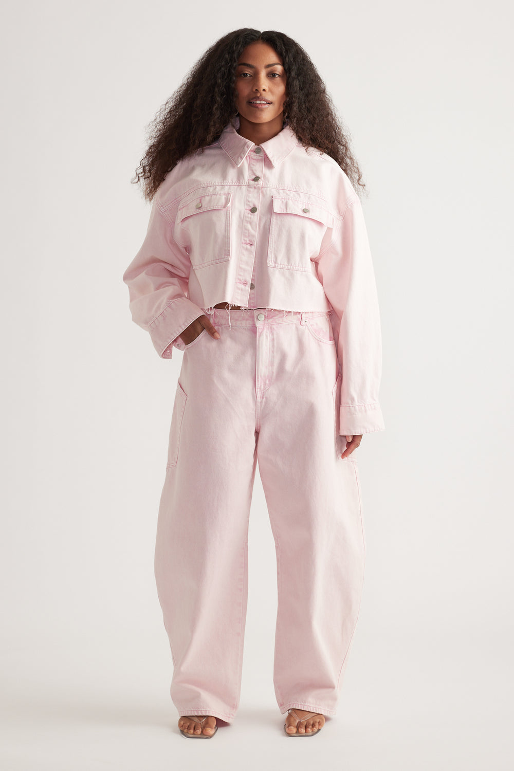 Woman wearing a cropped pink denim shirt with patch pockets and matching wide-leg jeans