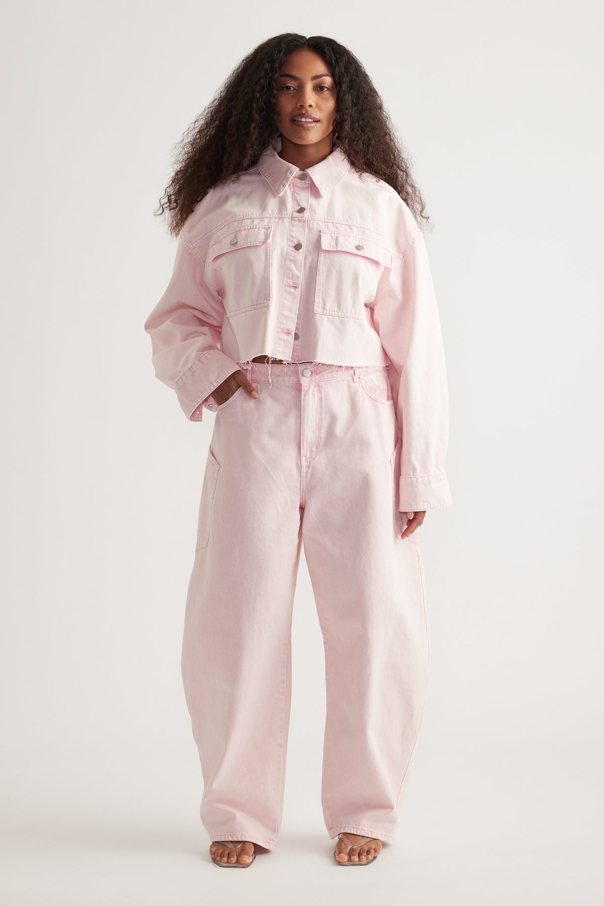 Woman wearing a cropped pink denim shirt with patch pockets and matching wide-leg jeans