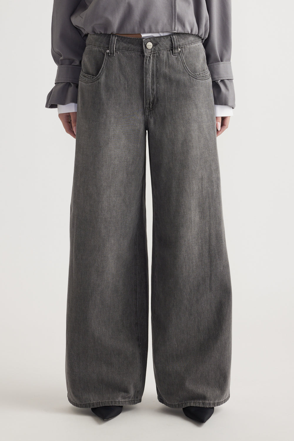 Front view of a mid-rise, wide-leg grey denim jean with belt loops and pockets worn with a grey top