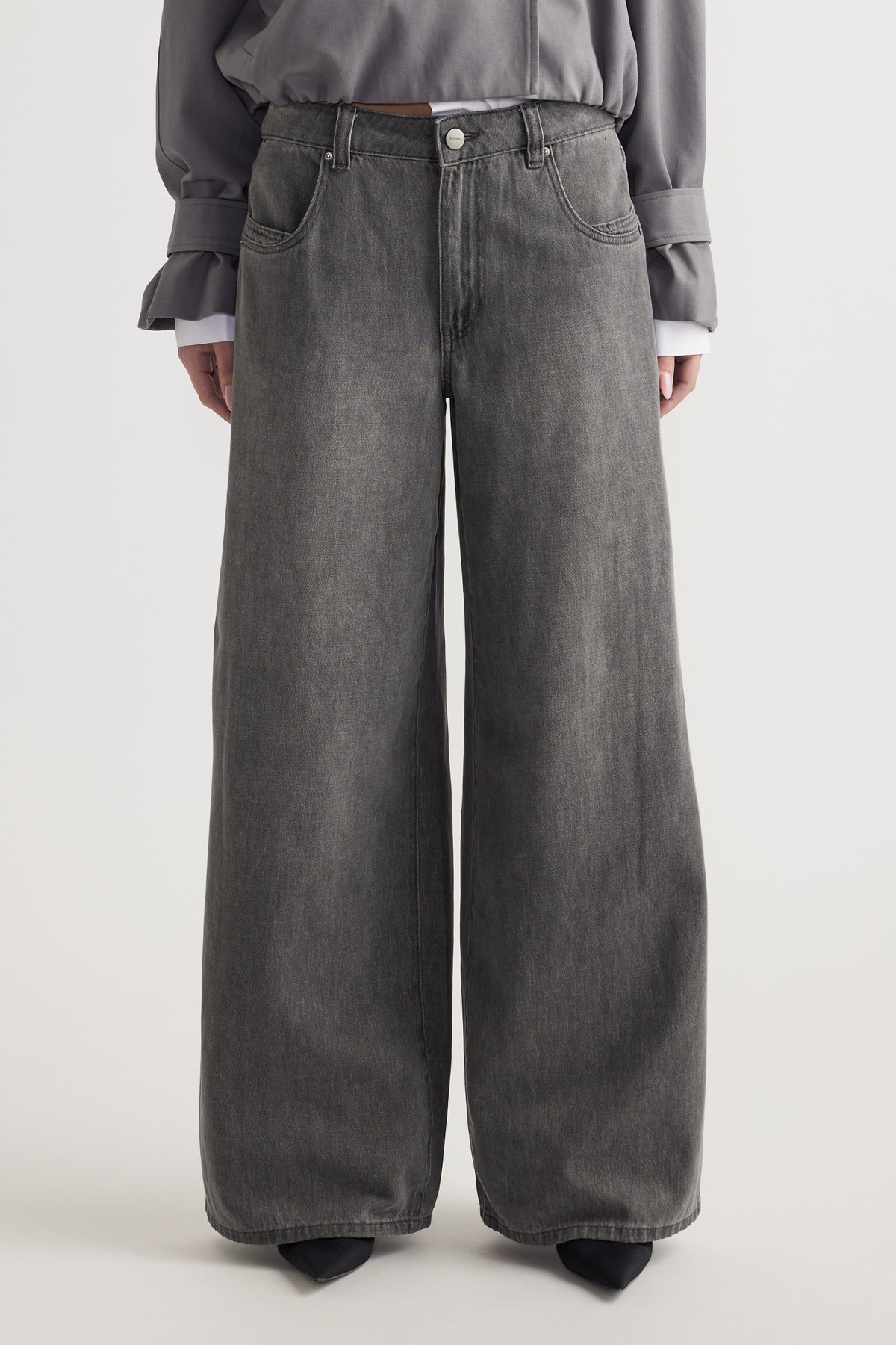Front view of a mid-rise, wide-leg grey denim jean with belt loops and pockets worn with a grey top