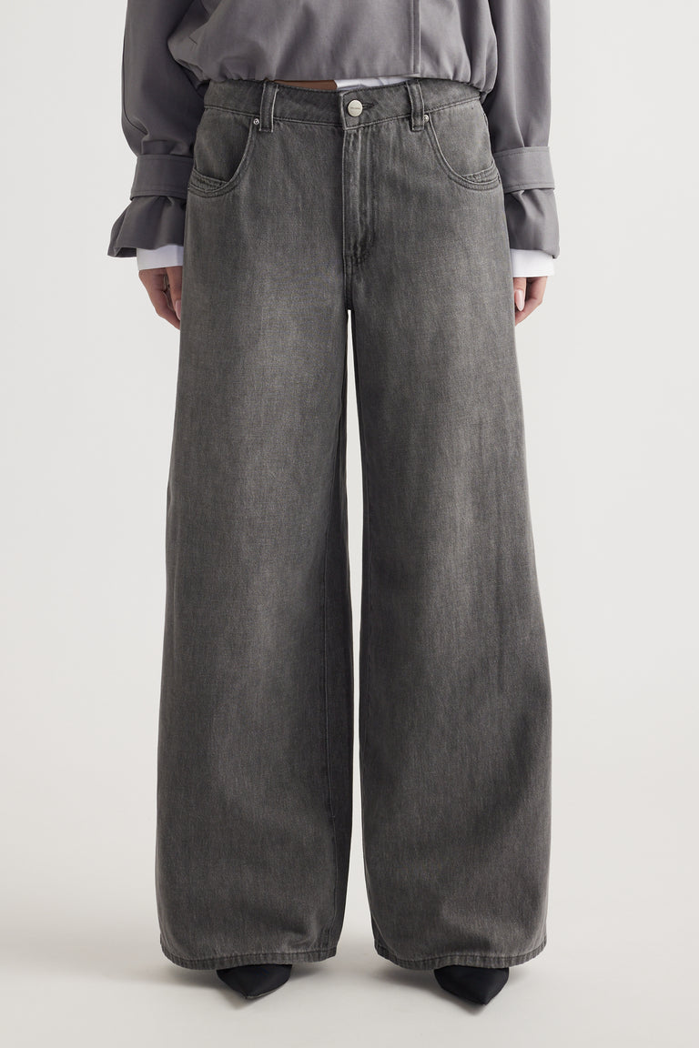 Front view of a mid-rise, wide-leg grey denim jean with belt loops and pockets worn with a grey top