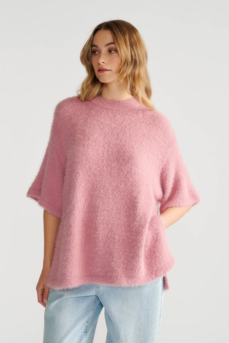 Woman wearing a soft pink oversized knit tee with elbow-length sleeves paired with light wash relaxed jeans.