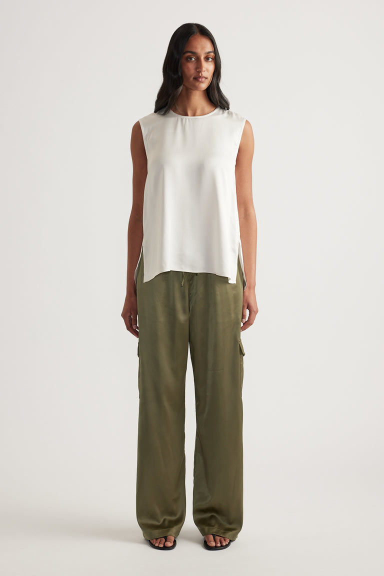 Woman wearing an ivory sleeveless high neck top with olive wide leg pants