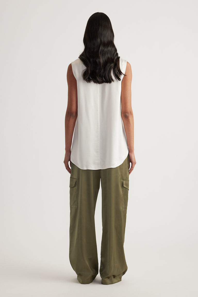 Back view of a woman wearing a white sleeveless high neck top with olive cargo pants