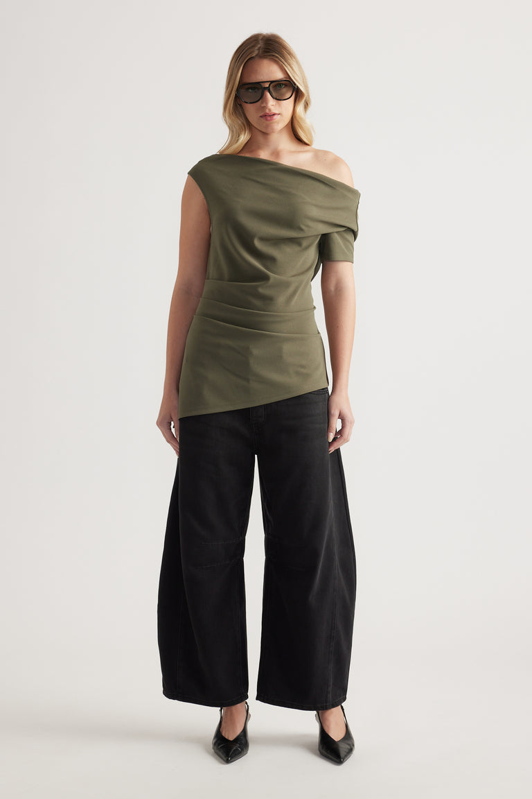 Woman wearing an olive off shoulder top with an asymmetric neckline and black wide leg pants