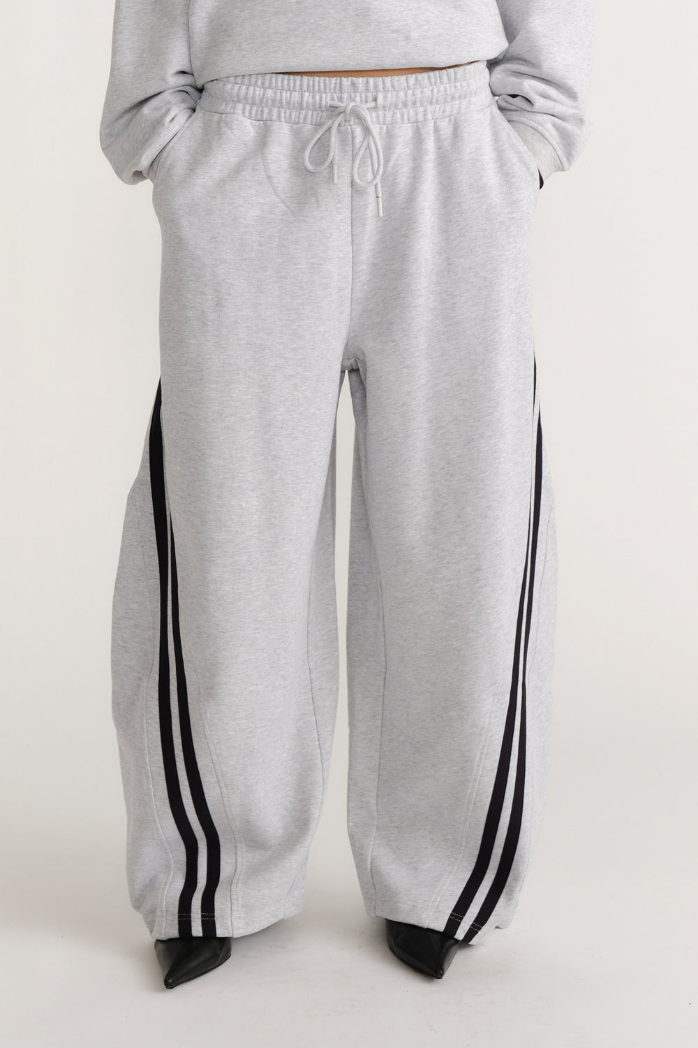 Light grey wide-leg trackpants with black side stripes and an adjustable drawstring waist for laid-back style