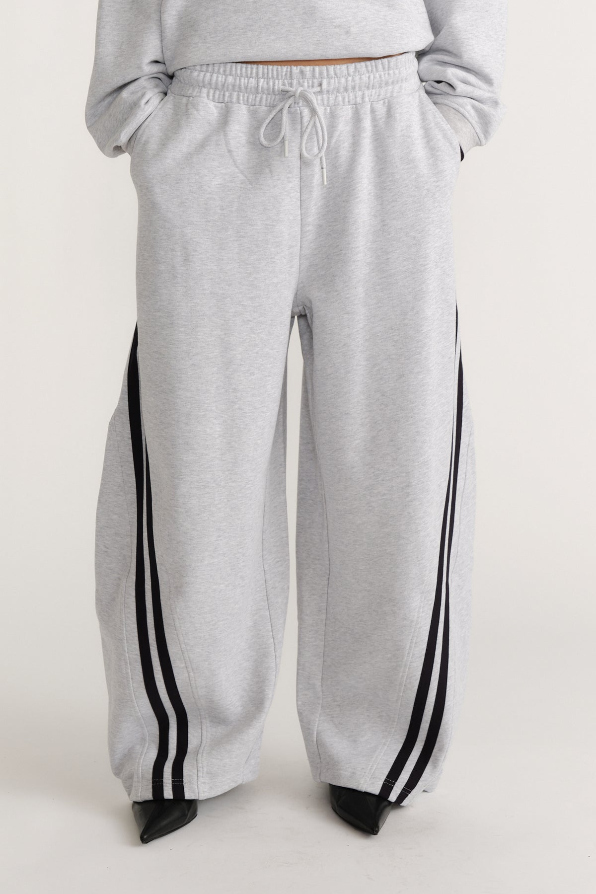 Light grey wide-leg trackpants with black side stripes and an adjustable drawstring waist for laid-back style