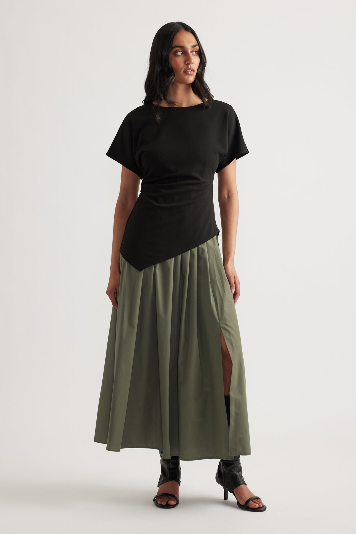 Woman wearing a black and olive spliced midi dress with short sleeves, round neck and pleated A-line skirt
