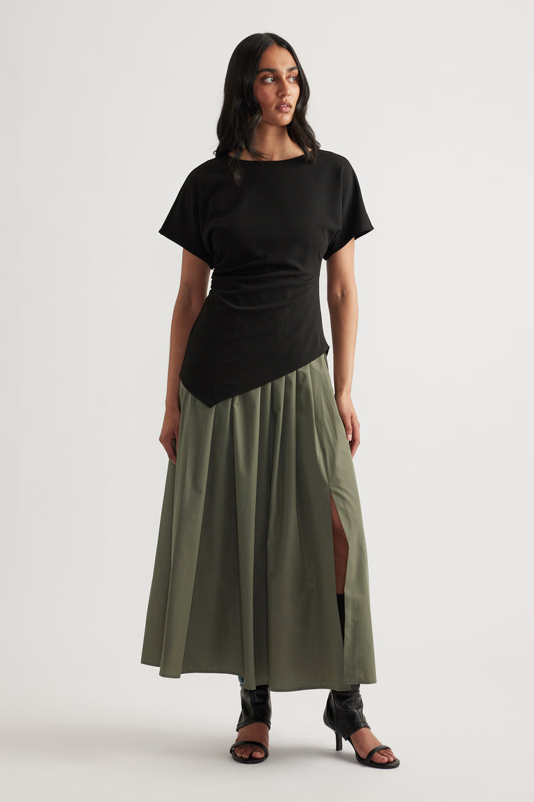 Woman wearing a black and olive spliced midi dress with short sleeves, round neck and pleated A-line skirt