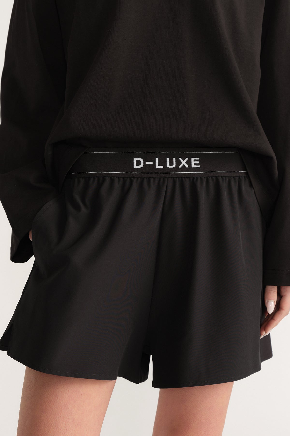 Woman wearing black D Luxe shorts with an elastic waist and flared above knee fit