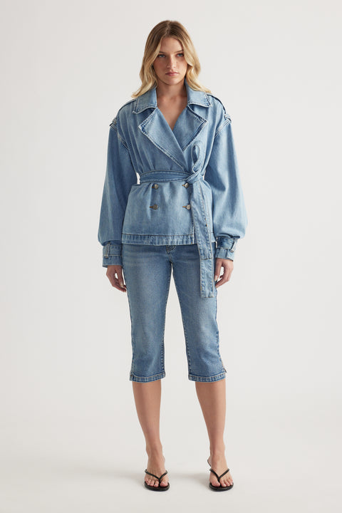 Woman wearing a belted denim jacket with cropped denim capri pants and strappy sandals