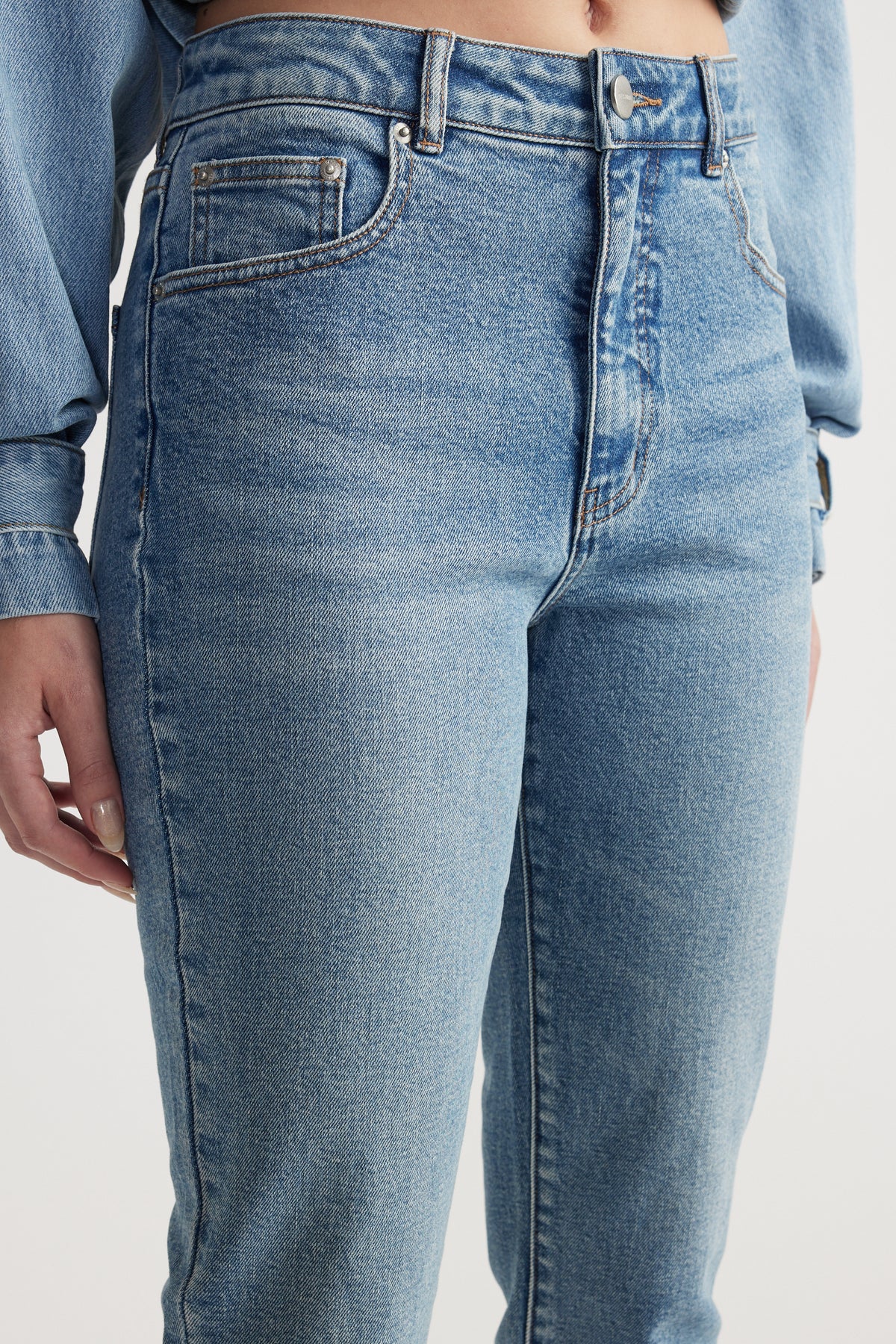 Close-up of a woman wearing high-rise light blue slim-fit denim capri pants
