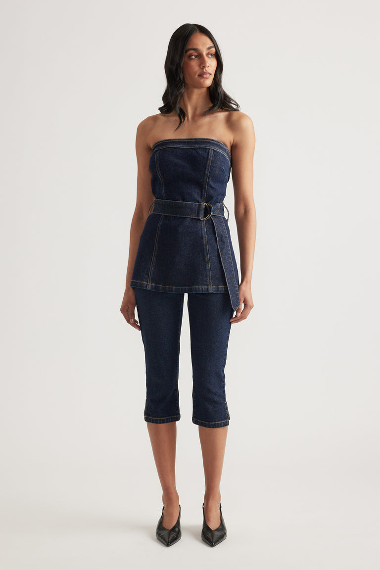 Woman wearing a strapless dark denim top with a belted waist and matching slim fit capri jeans