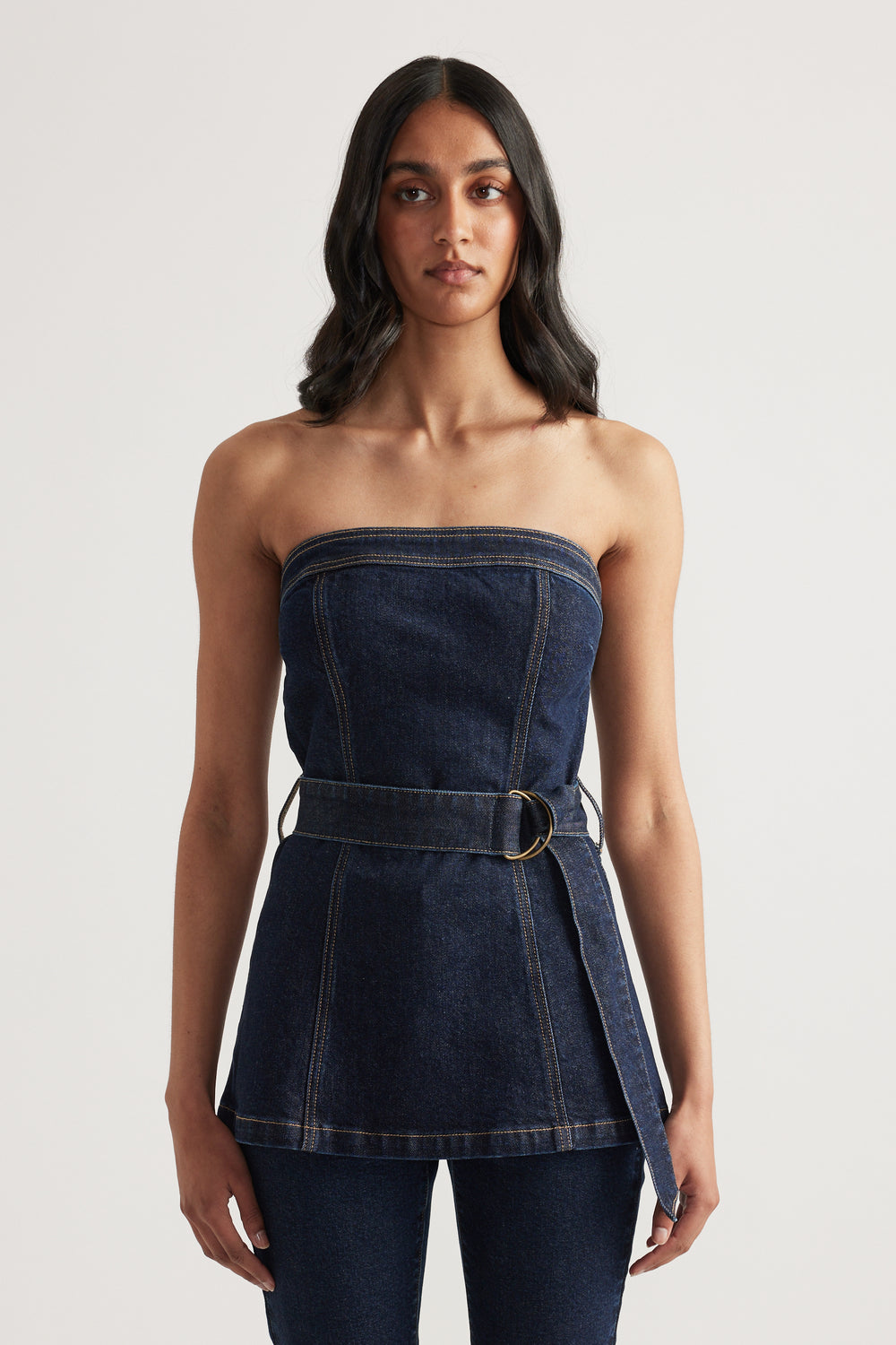 Woman wearing a dark denim strapless top with a belted waist and matching jeans
