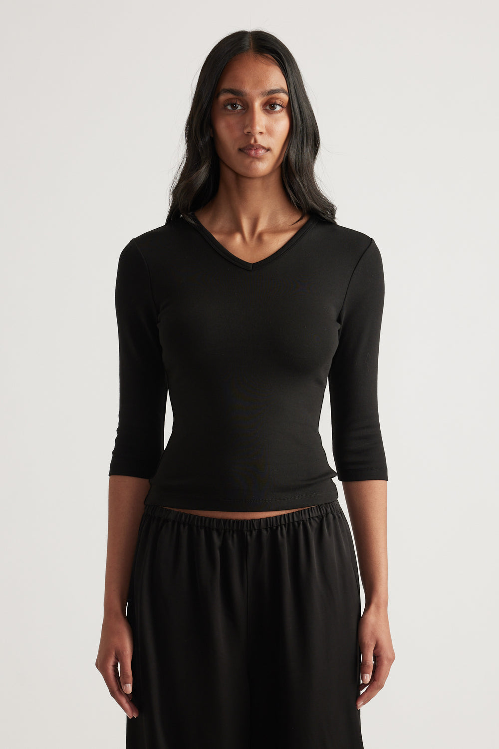 Woman wearing a black fitted V neck top with three quarter sleeves