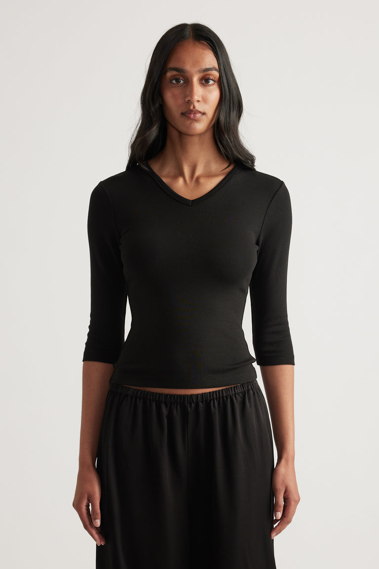 Woman wearing a black fitted V neck top with three quarter sleeves