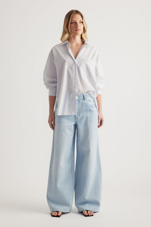 Woman wearing an oversized white collared shirt with light blue wide-leg jeans
