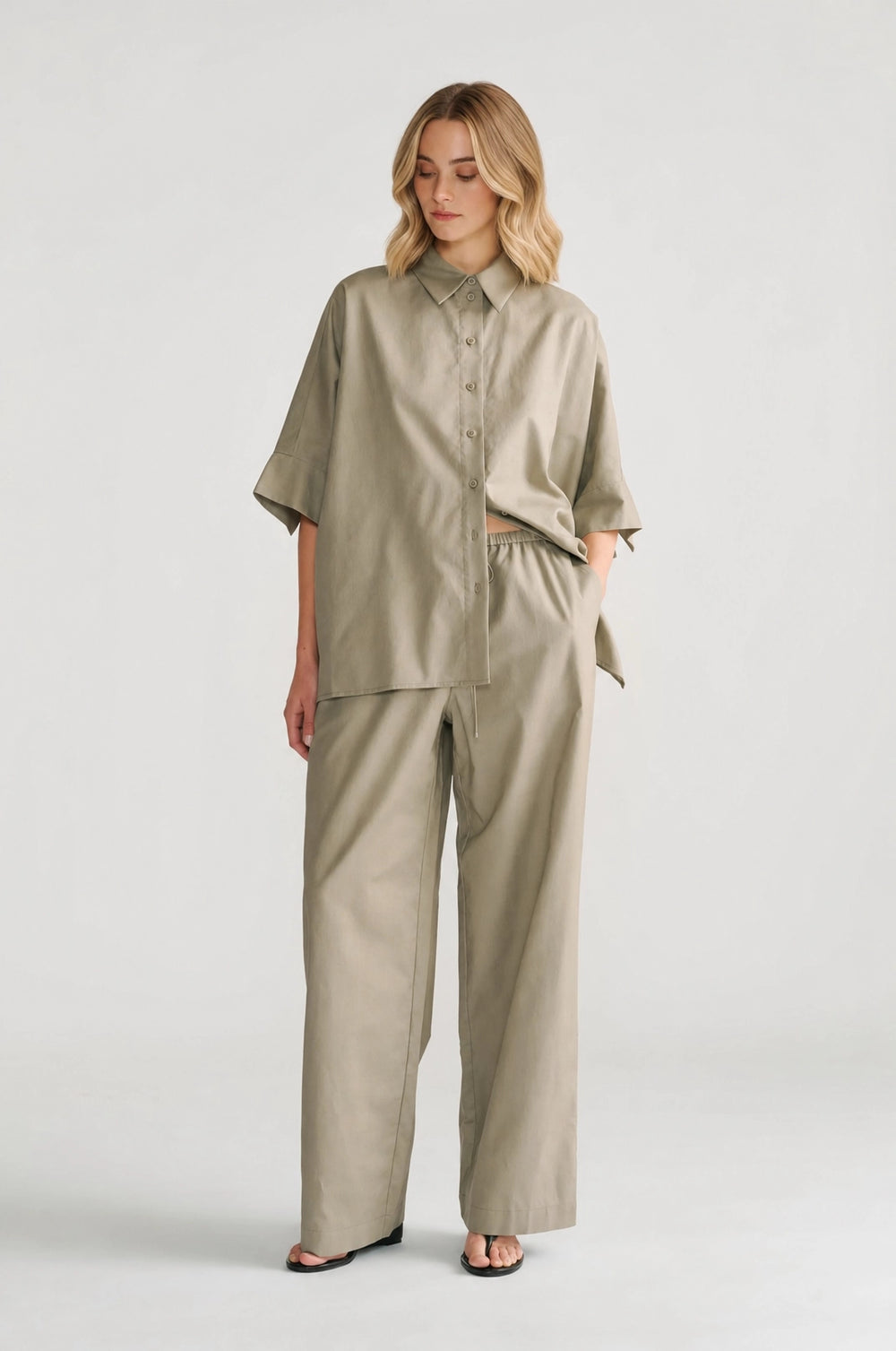 Woman wearing relaxed-fit sage oversized shirt with wide short sleeves paired with matching wide-leg pants