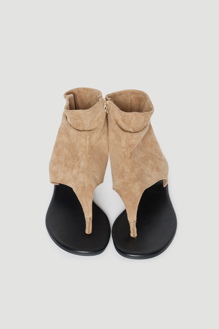 Pair of tan slouchy thong sandals with black flat soles and soft toe posts