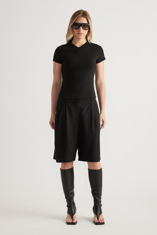 Woman wearing a black fitted V neck tee with black shorts and knee high boots