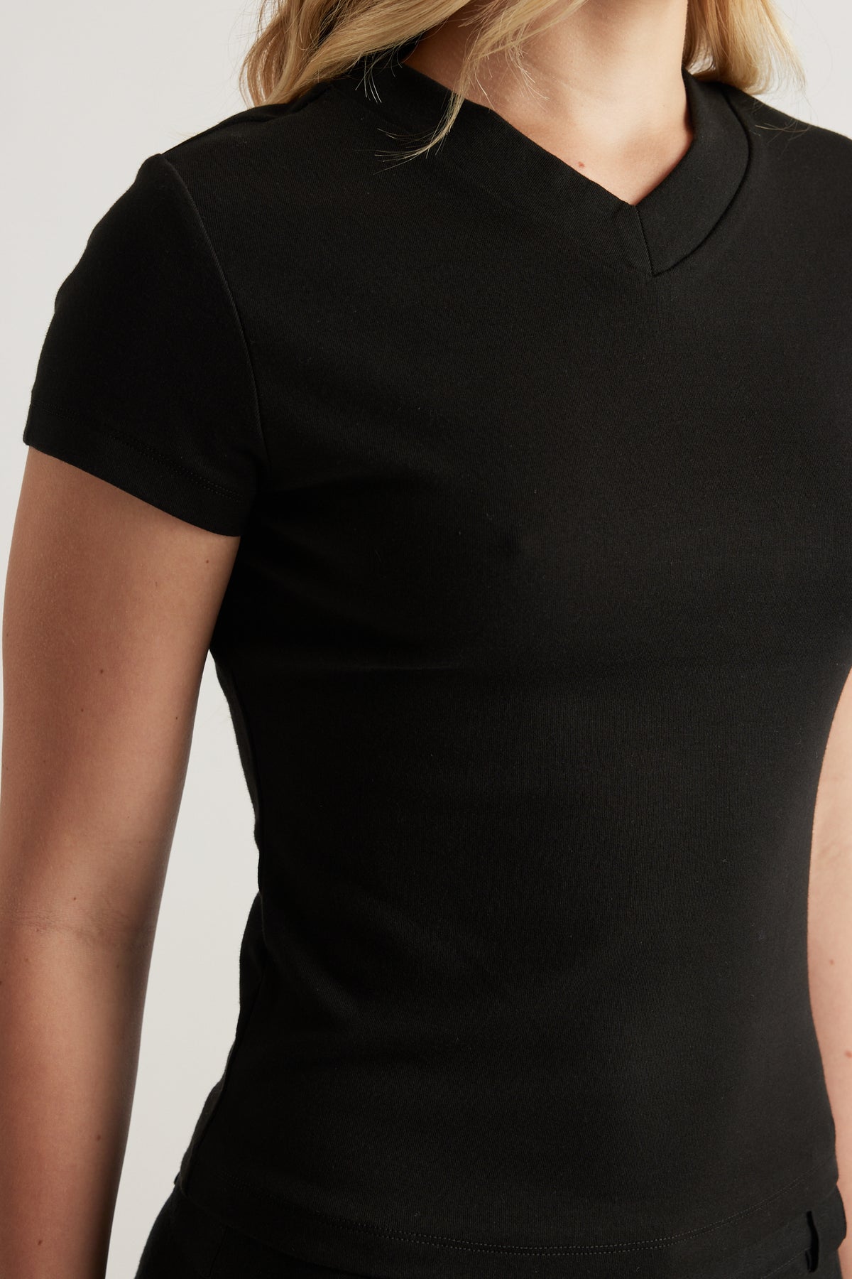 Woman wearing a fitted black short sleeve V neck tee